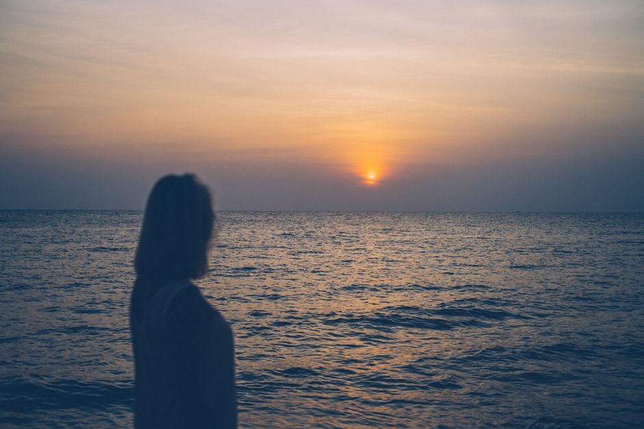 Silhouette gazing at ocean sunset