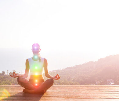 Beautiful woman sits in a pose of a half lotus on high place amazing view of the island outside, she practicing yoga meditation glowing seven all chakra eyes closed calm. Kundalini energy