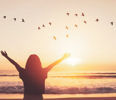 Copy space of woman raise hand up on sunset sky at beach and island with birds flying abstract background. Freedom and travel adventure concept. Vintage tone filter color style.